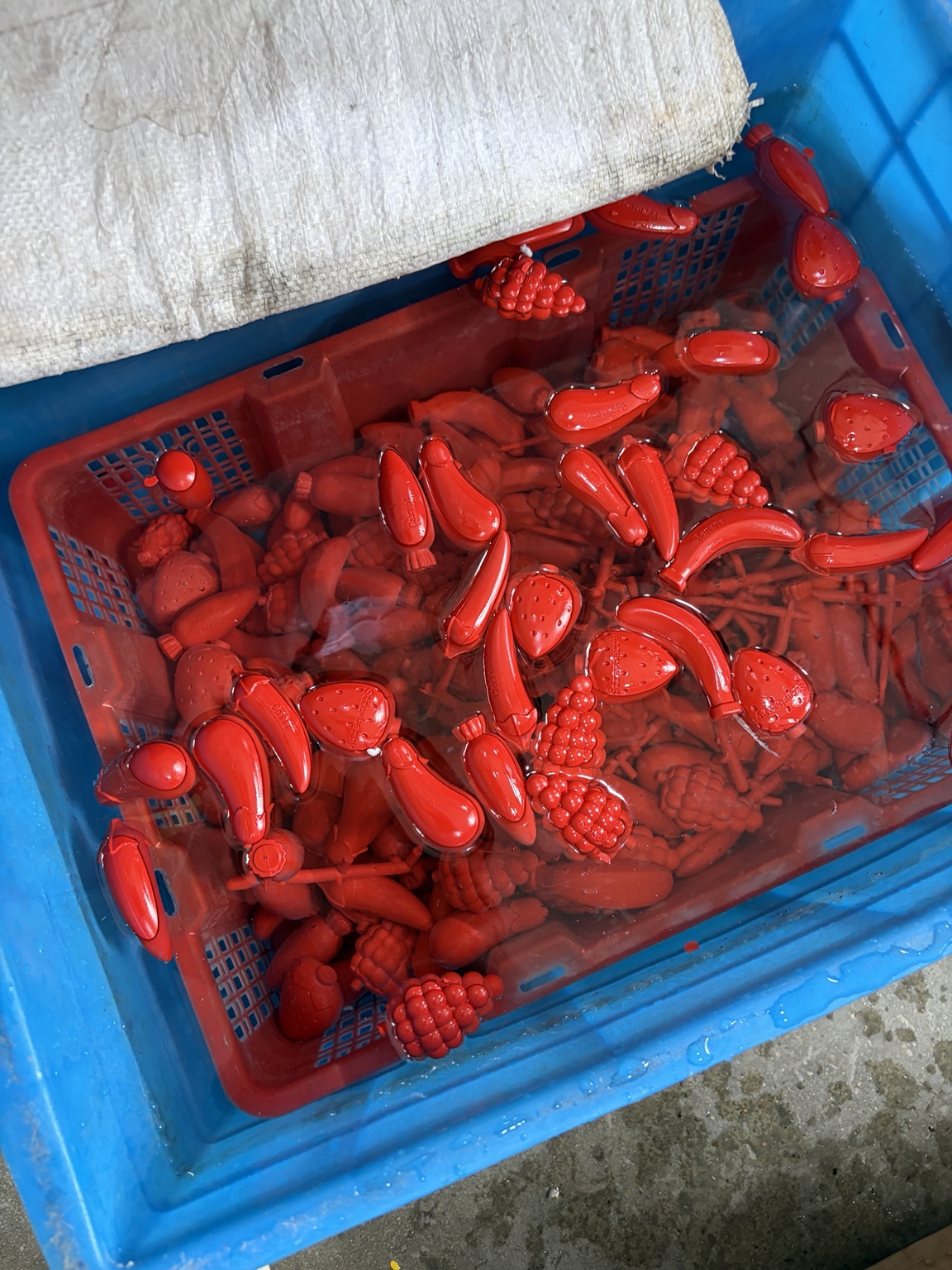 Batch of red fruit-shaped crayons in a production container
