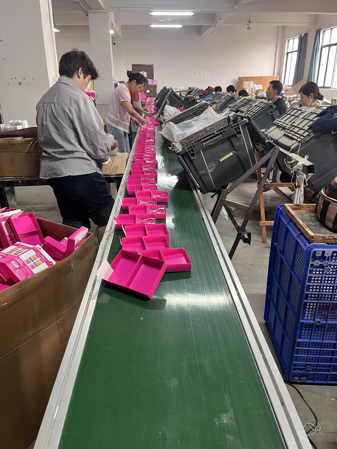 Close view of workers packing products into pink retail boxes